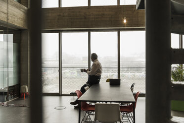 Senior Manager im Büro mit einer Tasse Kaffee in der Hand und ernstem Blick - UUF09912