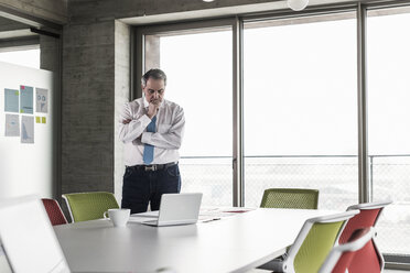 Senior manager in office looking worried at documents - UUF09939