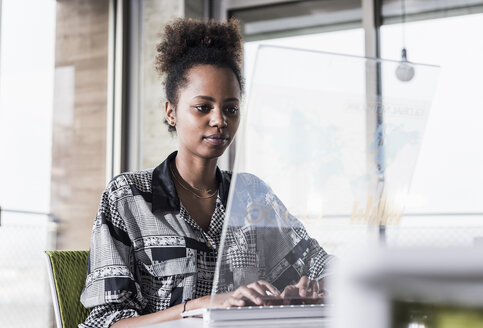 Junge Frau arbeitet im Büro an einem transparenten Computer - UUF09941