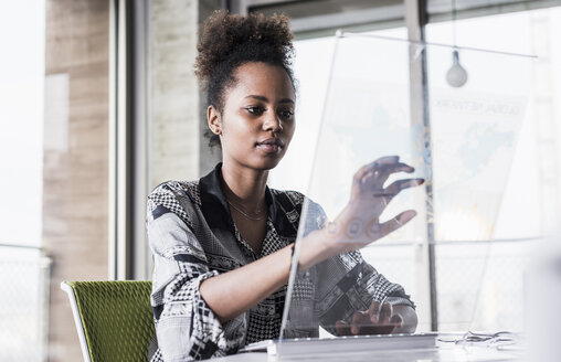 Junge Frau arbeitet im Büro an einem transparenten Computer - UUF09942