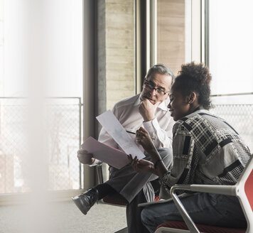 Senior manager discussing documents with young coworker - UUF09962