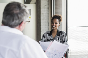 Senior manager discussing documents with young coworker - UUF09965