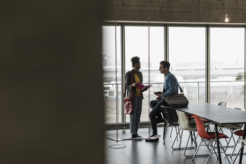 Junge Geschäftsleute besprechen Akten im Büro, lizenzfreies Stockfoto