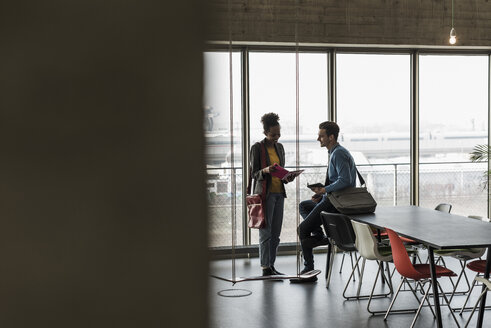 Junge Geschäftsleute besprechen Akten im Büro - UUF09970