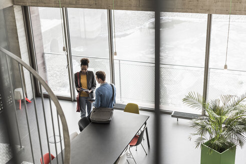 Junge Geschäftsleute besprechen Akten im Büro - UUF09973