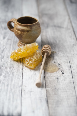 Honigwaben, Tontopf und Honiglöffel auf Holz, lizenzfreies Stockfoto