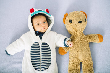 Neugeborenes Mädchen auf dem Bett in einem Bärenanzug neben einem Teddybär - GEMF01475