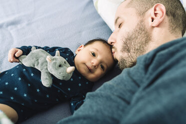 Father kissing his newborn baby girl on bed - GEMF01484