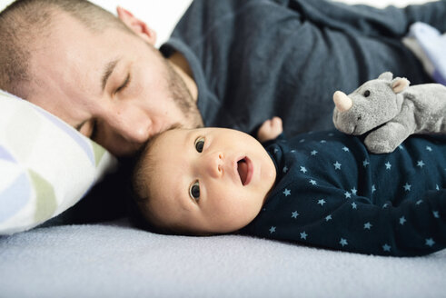 Vater küsst sein neugeborenes Mädchen im Bett - GEMF01486