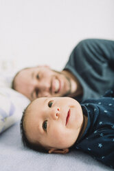 Glücklicher Vater liegt mit seinem neugeborenen Mädchen im Bett - GEMF01488