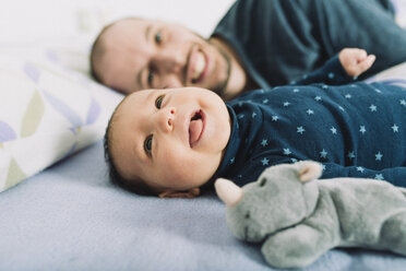 Happy father lying in bed with his newborn baby girl - GEMF01489