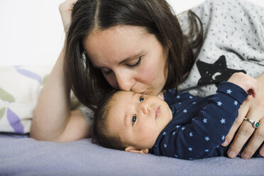 Mother lying in bed kissing her newborn daughter - GEMF01493