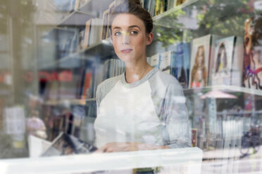 Young woman in a bookshop looking through window - LMF00612