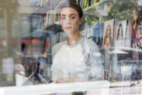 Junge Frau in einer Buchhandlung schaut durch ein Fenster - LMF00612
