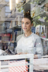 Junge Frau in einer Buchhandlung schaut durch ein Fenster - LMF00613
