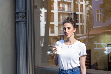 Junge Frau macht eine Kaffeepause vor einem Geschäft - LMF00621