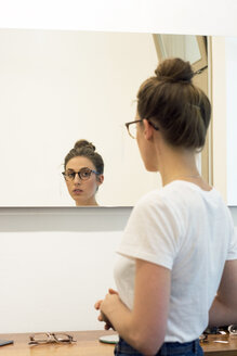Junge Frau testet Brillengestelle in einem Optikergeschäft - LMF00627