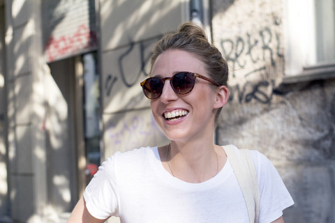 Porträt einer lachenden jungen Frau mit Sonnenbrille, lizenzfreies Stockfoto