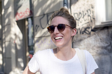 Portrait of laughing young woman wearing sunglasses - LMF00628