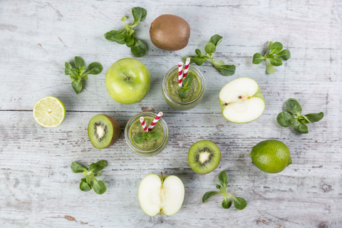 Two glasses of green smoothie and ingredients on wood stock photo