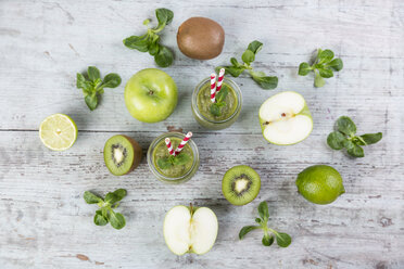 Zwei Gläser mit grünem Smoothie und Zutaten auf Holz - JUNF00857