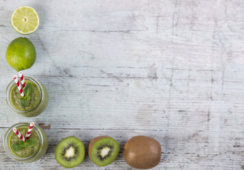 Two glasses of green smoothie and ingredients in a row on wood - JUNF00860