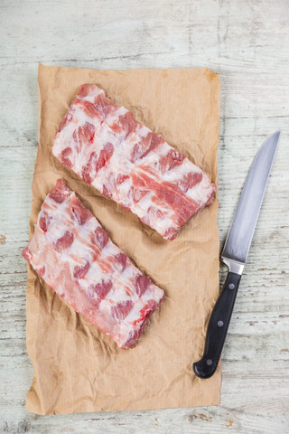 Rohe Spareribs auf braunem Papier und einem Messer, lizenzfreies Stockfoto