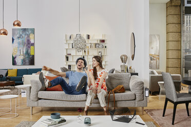 Couple in modern furniture store testing couch, being happy - RORF00577