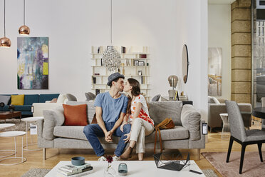Couple in modern furniture store sitting on couch, kissing - RORF00578