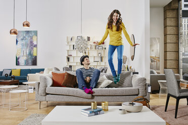 Pärchen in modernem Möbelhaus springt auf Couch - RORF00586