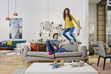 Couple in modern furniture store jumping on couch - RORF00591