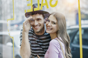 Young couple looking through window of a coffee shop - RORF00624