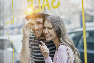 Young couple looking through window of a coffee shop - RORF00625