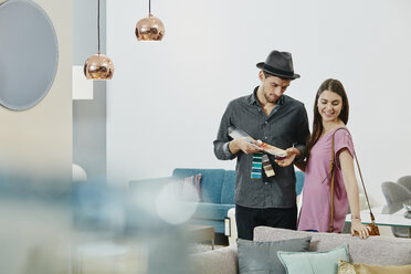 Couple in furniture store looking at color samples - RORF00636