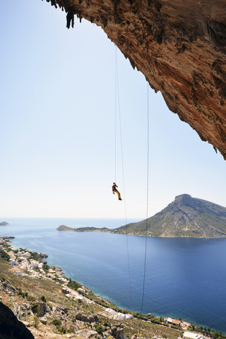 Greece, Kalymnos, climber abseiling in rock wall stock photo