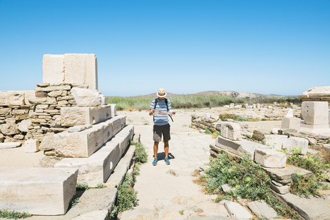 Griechenland, Mykonos, Delos, Tourist schaut auf Karte bei archäologischer Stätte, lizenzfreies Stockfoto