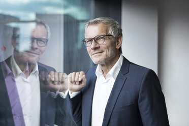 Confident businessman looking out of window - RBF05613