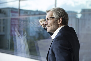 Confident businessman looking out of window - RBF05614