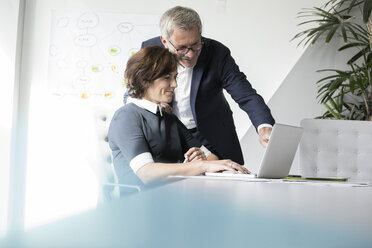 Geschäftsmann und Geschäftsfrau benutzen gemeinsam einen Laptop im Büro - RBF05624