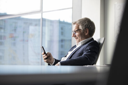 Geschäftsmann benutzt Mobiltelefon im Büro - RBF05630