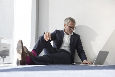 Geschäftsmann sitzt auf dem Boden und benutzt einen Laptop - RBF05639