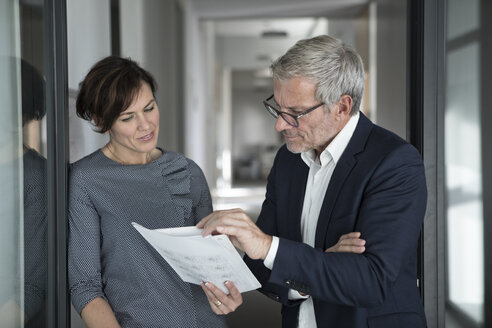 Geschäftsmann und Geschäftsfrau besprechen ein Dokument im Büro - RBF05650