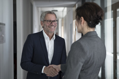 Geschäftsmann und Geschäftsfrau beim Händeschütteln im Büro - RBF05652