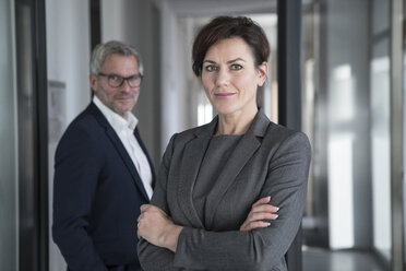 Portrait of confident businesswoman with businessman in background - RBF05655