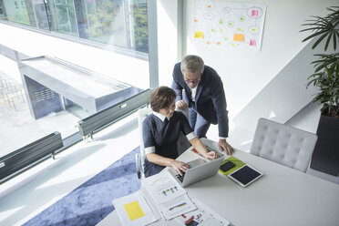 Businessman and businesswoman using laptop in office together - RBF05659