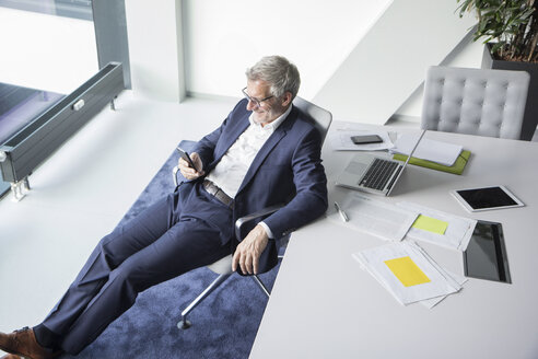 Smiling businessman using cell phone in office - RBF05660