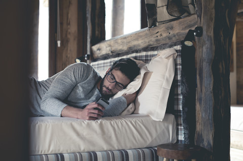 Young man using smartphone lying in bed at home stock photo