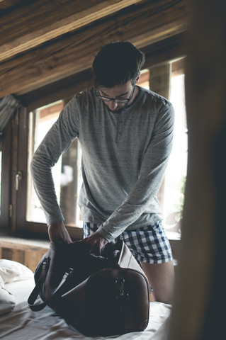 Young man making luggage for travel on bed stock photo