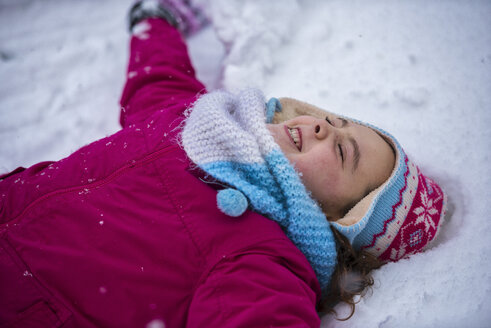 Lächelndes Mädchen macht einen Schneeengel - LOMF00514