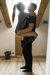 Amorous couple standing at home, kissing and ambracing passionately - KKAF00465